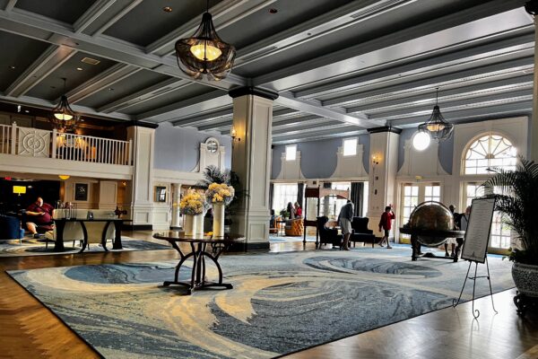 Elegant hotel lobby with grand staircase, chandeliers, and large globe, fitting for Disney World resorts for adults.