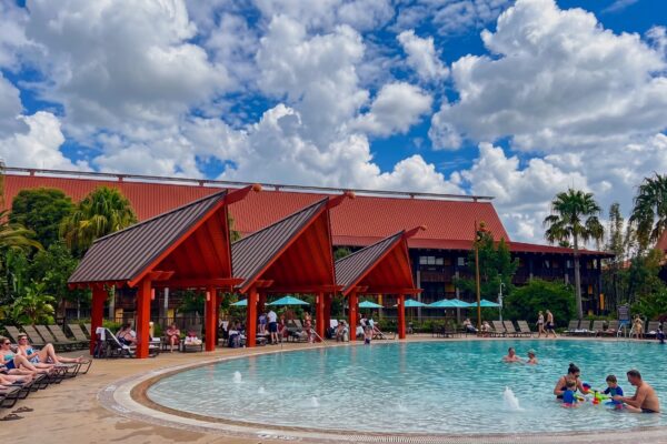Polynesian Village Resort pool area with lounge chairs and guests enjoying the water.
