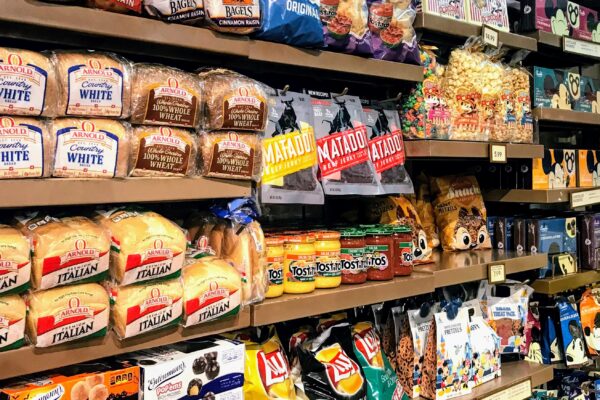 Grocery store shelves stocked with bread, snacks, and drinks for hotel delivery.