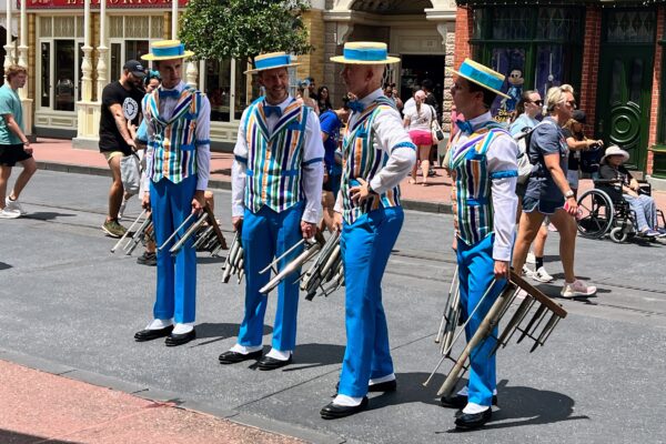 Four performers in matching blue and white striped outfits with straw hats at Magic Kingdom