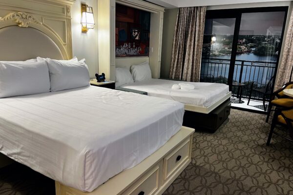 Two queen beds in a DVC room with a view of a lake and balcony.