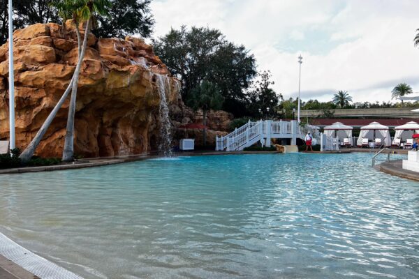 Resort pool with rock waterfall, lounge chairs, and cabanas, perfect for a Disney bachelorette weekend.