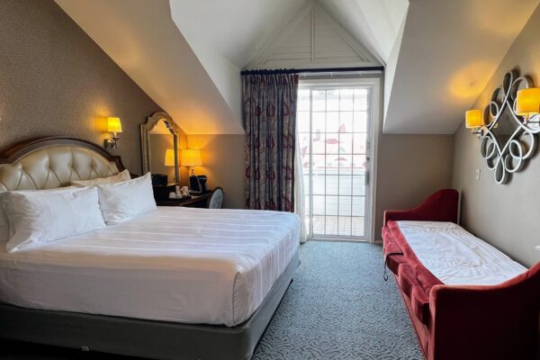Disney room with king bed, pull-out sofa, and balcony door