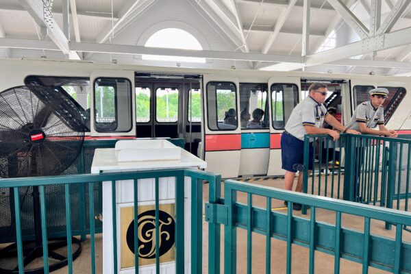 Disney monorail with cast members and guests at a station