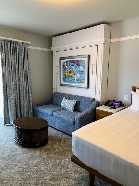 DVC resort room with Murphy bed, sofa, and Disney art