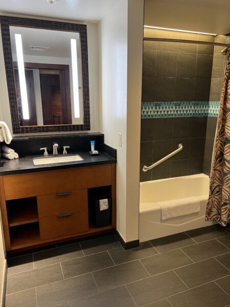 Disney hotel bathroom with tub, shower, vanity, and mirror.