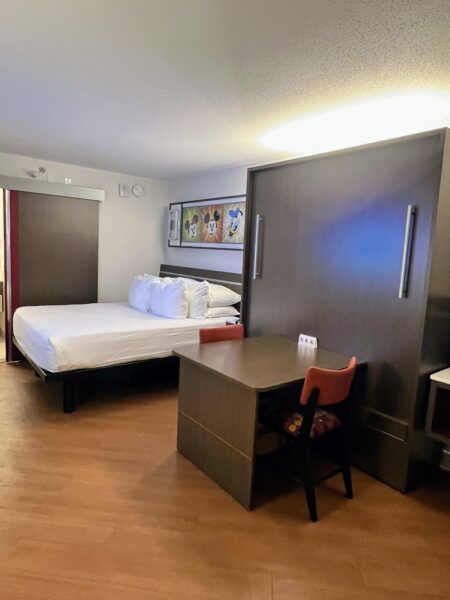 Disney hotel room with a murphy bed, desk, and Mickey Mouse art