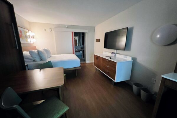 Disney room with queen bed, TV, and desk, showing adult capacity.