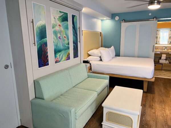 Disney resort room with murphy bed, sofa, and ocean mural