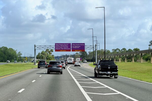 Cars on highway approaching Disney World signs for Magic Kingdom and resorts