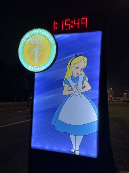 Lit-up Mile 1 marker with a race clock on a dark runDisney course