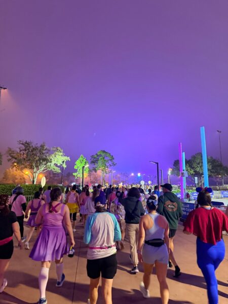 Runners in costumes walking to the start corrals in the dark before a runDisney race